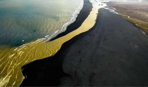 Amazing place in Iceland where a yellow river meets a black beach and blue  sea.